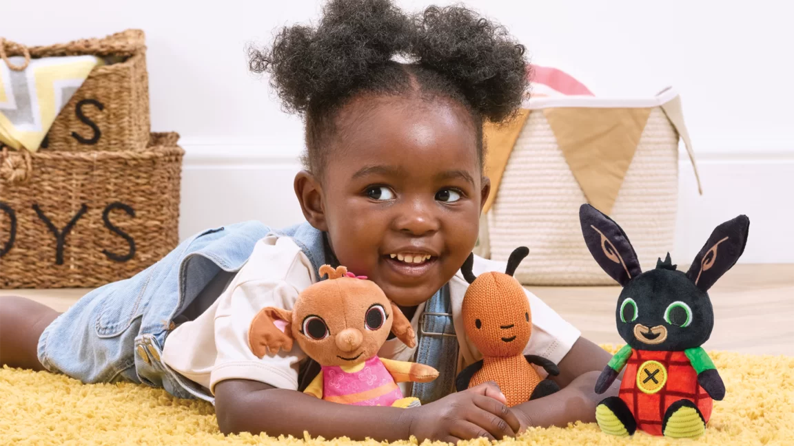 Girl laying down with Flop Bing and Sula toys in front of her