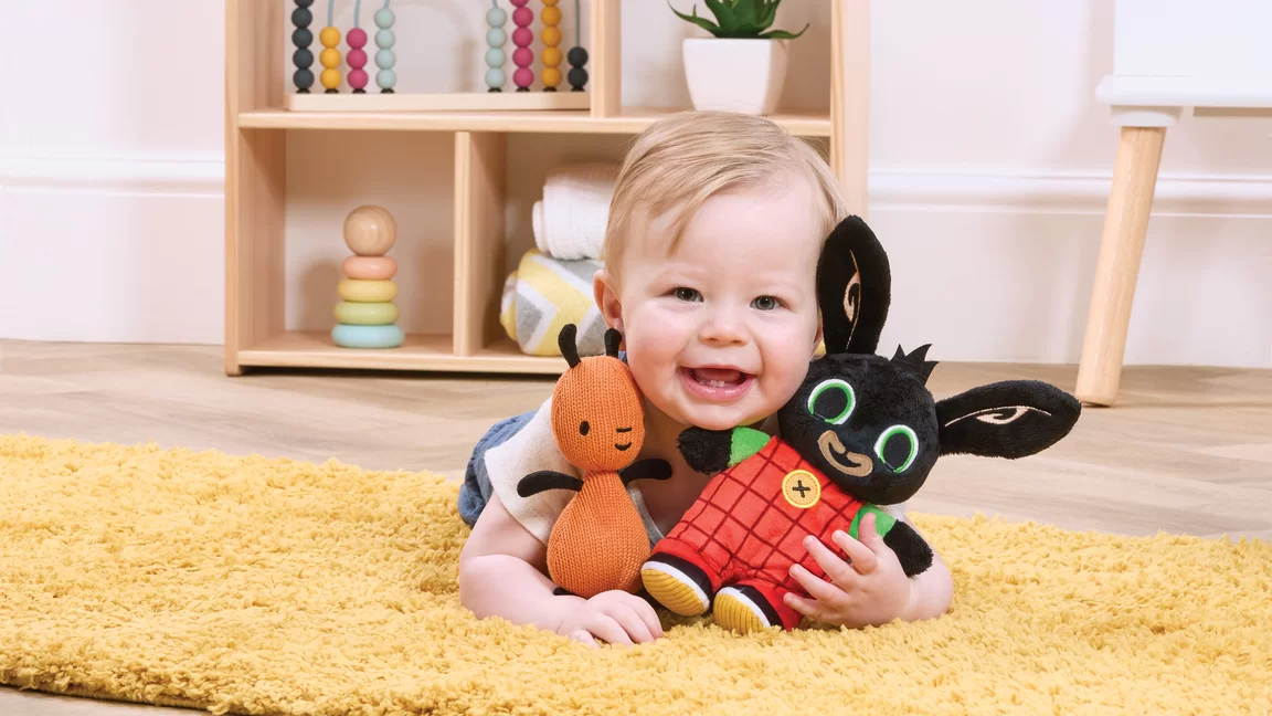 baby holding flop and bing plush